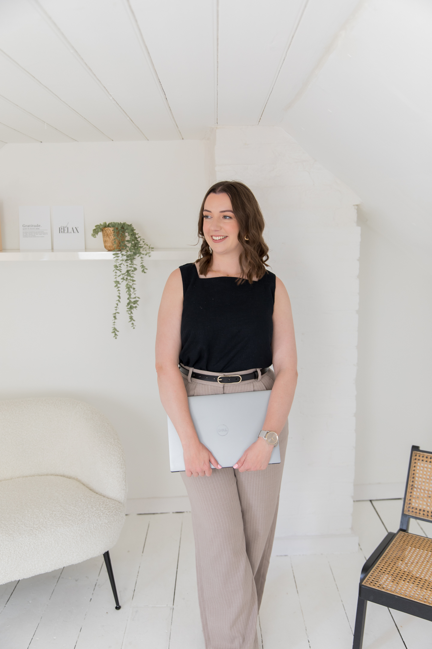 A Wedding Photographer Virtual Assistant standing whilst holding a closed laptop in her hands.