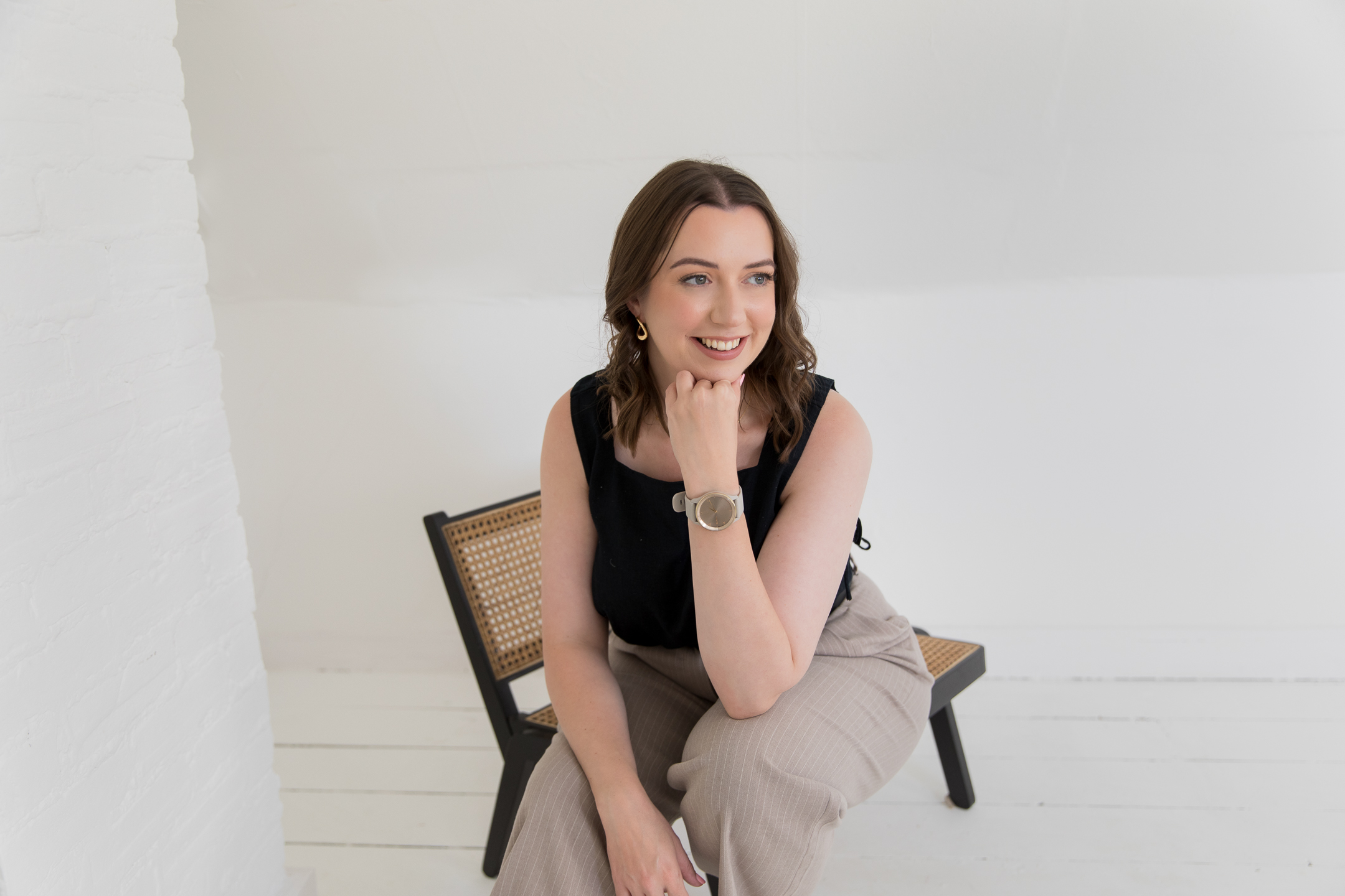 A UK based Virtual Assistant sitting on a chair whilst smiling and ready to talk to wedding businesses.